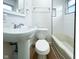 Bright bathroom with a pedestal sink, toilet and white tiled tub and shower at 5103 E St Clair St, Indianapolis, IN 46219