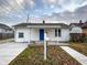 Quaint white one-story home featuring a blue front door and a well-maintained yard at 5103 E St Clair St, Indianapolis, IN 46219