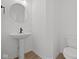 Stylish powder room featuring a pedestal sink, round mirror, and modern fixtures at 5119 Rolling Meadow Blvd, Indianapolis, IN 46237