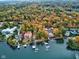 Luxury waterfront home with boat dock surrounded by lush trees in colorful autumn foliage at 6842 Cardinal Dr, McCordsville, IN 46055