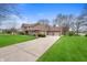Side view of a two-story brick home featuring a three-car garage and lush green lawn at 7018 W Anton Way, New Palestine, IN 46163