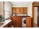 Functional laundry room with oak cabinets, counter space, and a hidden washer-dryer combo at 7018 W Anton Way, New Palestine, IN 46163