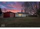 Backyard view at dusk featuring a red shed, white privacy fence, and a single-story house at 1408 W Banta Rd, Indianapolis, IN 46217