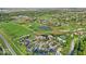 High-angle aerial shot showcases golf community amenities, including fairways, clubhouse, ponds, and tennis courts in a green setting at 16473 Valhalla Dr, Noblesville, IN 46060