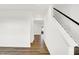 Hallway featuring laminate flooring, white walls, and a staircase with black handrail that leads to the upper level at 2004 Foothill Dr, Greenfield, IN 46140