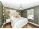 Bright bedroom featuring a decorative mural wall, wooden floors, and natural light from the large window at 401 W Westfield Blvd, Indianapolis, IN 46208