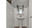 A clean powder room with a pedestal sink, subway tile walls, and a window for natural light at 4040 Jacoby Pl, Indianapolis, IN 46268