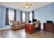 Well-lit home office with modern desk setup, comfortable sofa, ceiling fan, and wood-look floors at 5147 Nicodemus Dr, Plainfield, IN 46168