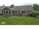 A charming backyard featuring a sunroom, lush lawn, and a relaxing chair at 6564 Aintree Pl, Indianapolis, IN 46250