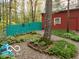 A rustic barn with red siding and a turquoise fence nestled among trees, with a stone pathway at 7166 N Oak Ridge Rd, Morgantown, IN 46160