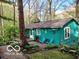 A cozy turquoise cottage sits among mature trees and landscaping, offering a serene and private setting at 7166 N Oak Ridge Rd, Morgantown, IN 46160