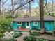 Charming turquoise home with a cozy front porch, surrounded by lush greenery and a stone pathway at 7166 N Oak Ridge Rd, Morgantown, IN 46160