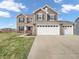 Charming two-story home featuring a three-car garage, brick and vinyl siding, and a well-maintained lawn at 976 Cherry Tree Ln, Greenwood, IN 46143