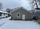 A snow-covered backyard features a single window and door with stone siding at 1105 Winfield Ave, Indianapolis, IN 46222
