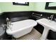 Mint-walled bathroom boasts clawfoot tub, pedestal sink, and classic black and white tile floor at 1409 N Park Ave, Indianapolis, IN 46202