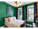 Charming bedroom boasts emerald walls, vintage light fixture, and views from two bright windows at 1409 N Park Ave, Indianapolis, IN 46202