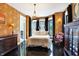 A spacious primary bedroom with dark wood floors, bay windows, decorative chandelier, and antique decor at 1409 N Park Ave, Indianapolis, IN 46202