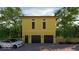 New construction, two-story, yellow, two-car garage with an automobile parked outside on a brick driveway at 1409 N Park Ave, Indianapolis, IN 46202