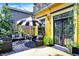 Charming outdoor seating area with a black and white umbrella, lush plants, and access to the bright yellow home at 1409 N Park Ave, Indianapolis, IN 46202