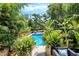 Backyard featuring a sparkling blue pool surrounded by lush greenery and tropical plants, creating a private oasis at 1409 N Park Ave, Indianapolis, IN 46202