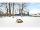 Snow-covered backyard with a modern home, firepit, and leafless trees on a partially cloudy day at 150 W Jo Jo Ln, Nineveh, IN 46164