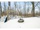 Snowy backyard featuring a fire pit and wooden swing set, set amidst a tranquil wooded area at 150 W Jo Jo Ln, Nineveh, IN 46164