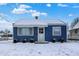 Charming blue home featuring a snow-covered yard, classic design, and inviting entrance at 1651 Lawton Ave, Indianapolis, IN 46203