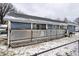 Home exterior featuring a covered porch with lattice detailing and a chain link fence on a snowy day at 2758 S Lyons Ave, Indianapolis, IN 46241