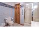 Bathroom with blue wallpaper and white toilet next to a wooden closet door and glass shower at 2979 Colony Lake E Dr, Plainfield, IN 46168