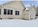 Back exterior featuring a cream door and windows with a snow-covered lawn at 5791 Station Hill Dr, Avon, IN 46123