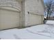 Attached garages with an arched brick entryway on a snow-covered driveway and yard at 5791 Station Hill Dr, Avon, IN 46123