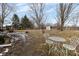 Spacious backyard with a wrought-iron table set, mature trees, and partial snow cover at 7968 E 200 S, Whitestown, IN 46075