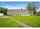 Spacious backyard with a well-maintained lawn, mature trees, and the exterior of the home at 9841 E Raymond St, Indianapolis, IN 46239