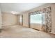 Large living room with classic decor, featuring patterned curtains, light fixture, and neutral carpeting at 9841 E Raymond St, Indianapolis, IN 46239