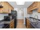Galley kitchen with wood cabinets, black appliances, and neutral countertops at 2829 Country Estates Dr, Indianapolis, IN 46227