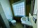 This cozy bathroom is fitted with a pedestal sink and a classic toilet, illuminated by a glass block window at 3236 Central Ave, Indianapolis, IN 46205