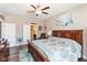 Cozy bedroom features wood furniture, ceiling fan, and view into the ensuite bathroom at 3629 S Meadows Ln, New Palestine, IN 46163