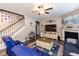 Cozy living room featuring a fireplace, ceiling fan, and a staircase adorned with Gathering photos at 3629 S Meadows Ln, New Palestine, IN 46163