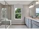 Neutral-toned bathroom featuring a glass shower, double vanity with quartz countertop, and a serene window view at 5314 Pelion Pl, McCordsville, IN 46055