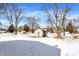 Snow covered backyard with a shed, surrounded by bare trees and a blue sky at 5614 Personality Ct, Indianapolis, IN 46237