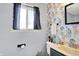 Cozy bathroom with vibrant floral wallpaper, vanity with sink, and a window that provides natural light at 5614 Personality Ct, Indianapolis, IN 46237