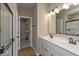 Bathroom featuring double sinks with white cabinets, dark faucets, and a large mirror at 7367 Broadview Ln, McCordsville, IN 46055