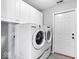 Well-lit laundry room featuring a white washer and dryer set, and ample cabinet space for storage at 7415 Chapel Villas Dr # D, Indianapolis, IN 46214