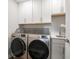 Modern laundry room with stainless steel washer and dryer, white cabinets, and a sink at 8660 Hudson Way, Brownsburg, IN 46112