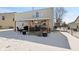A snowy backyard features a covered patio with dining set, grill, and a cozy outdoor space at 10404 Kings Gap Way, Indianapolis, IN 46234