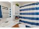 A functional bathroom with a blue and white striped shower curtain, and a white vanity with dark wood accents at 10404 Kings Gap Way, Indianapolis, IN 46234