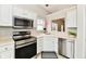 Close-up of the kitchen area featuring stainless steel appliances, white cabinets, and a view into an adjacent room at 10669 Springston Ct, Fishers, IN 46037
