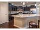 Well-lit kitchen with stainless steel appliances, dark cabinets, granite countertops, and an island with barstool seating at 12991 Pennington Rd, Fishers, IN 46037