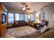 Comfortable living room featuring hardwood floors, ceiling fan, large windows, and an entertainment center at 12991 Pennington Rd, Fishers, IN 46037