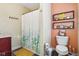 Cozy bathroom featuring a shower with leaf-patterned curtain, decorative shelves, and peach accent wall at 1390 Greenfield Ave, Noblesville, IN 46060